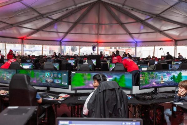In einem Zelt sind 100 GamingPCs mit Bildschirmen aufgebaut, dort spielen viele Jugendliche Fortnite