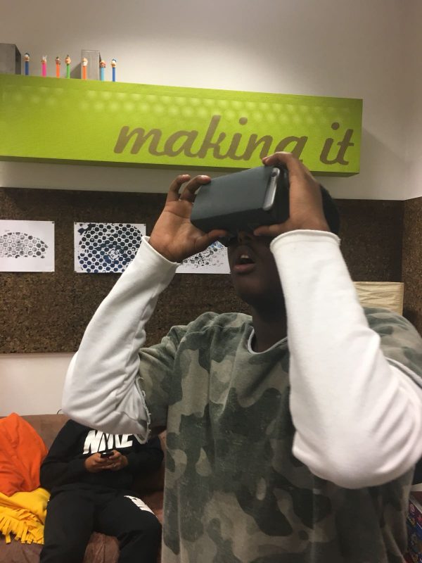 Ein Bursche hält sich eine VR-Brille vor die Augen und hat staunend den Mund geöffnet.