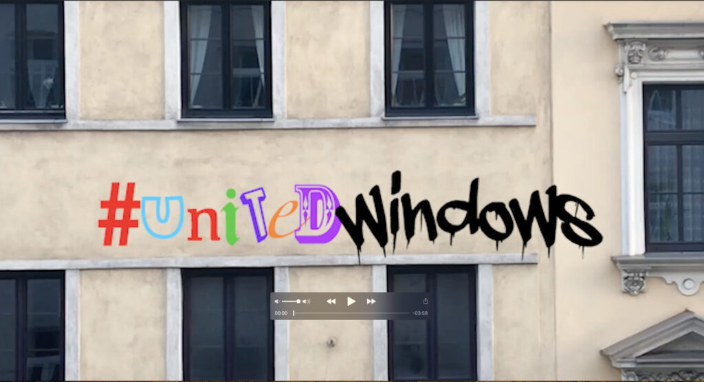 Foto einer eher dreckigen und gelben Häuserwand mit vielen Fenstern. Darüber steht in bunten Lettern geschrieben: #UnitedWindows.