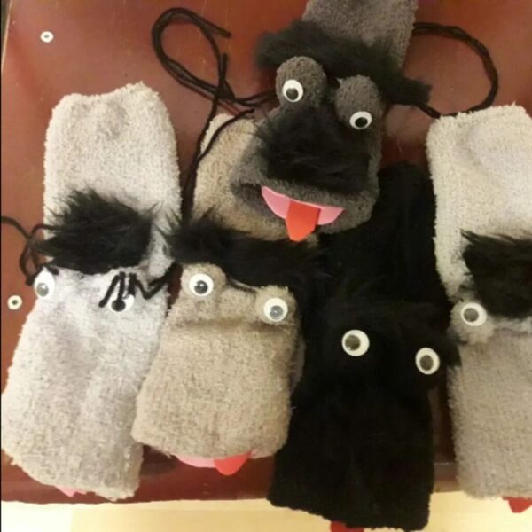 Das Bild zeigt fünf Sockenpuppen mit Wackelaugen und herausgestreckten Zungen.