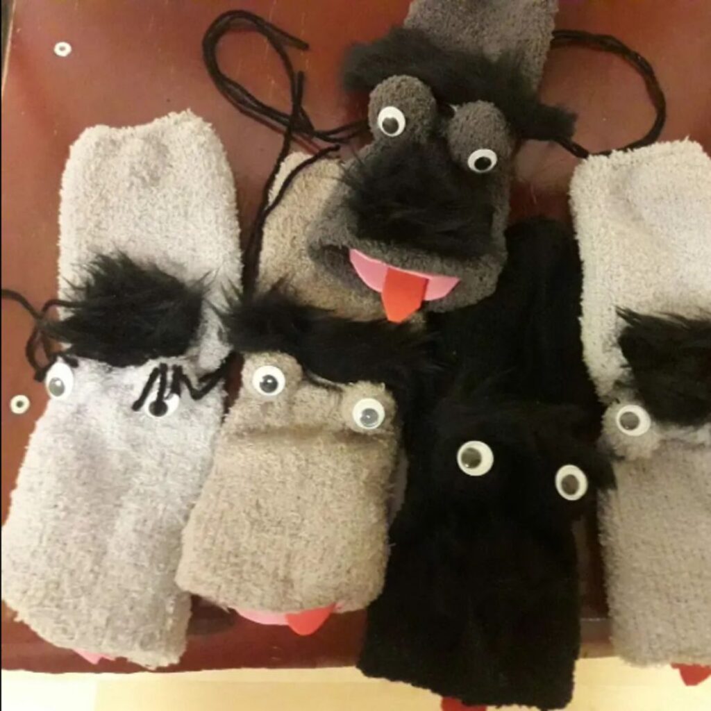 Das Bild zeigt fünf Sockenpuppen mit Wackelaugen und herausgestreckten Zungen.
